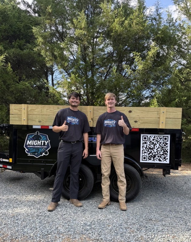 Tallas and David, owners of Mighty Dump and Demolition, with their junk removal trailer in Charlotte NC
